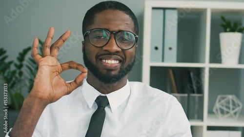 African man posing on camera and raising thumbs up to showing that everythink is OK. Close up. photo