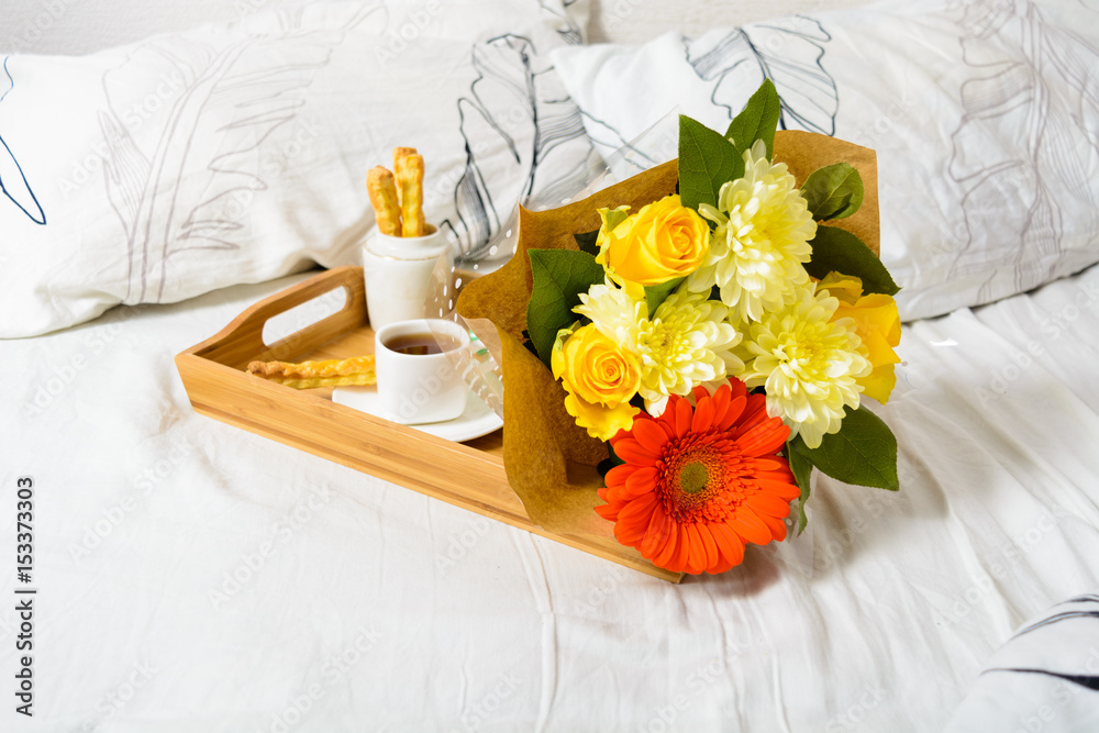 Tray with coffee, snack and bouquet of flowers on bed Tray with coffee, snack and bouquet of flowers on bed