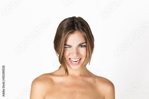 Beautiful and young woman with short blond hair and bare shoulders making funny faces