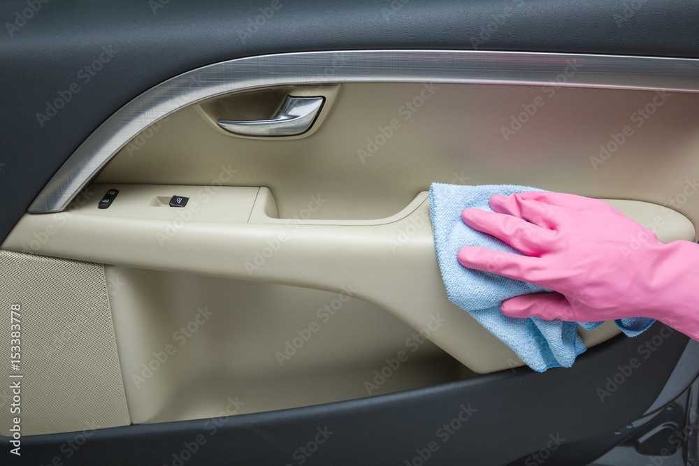 Hand in rubber protective glove with rag cleaning a car interior's door. Early spring cleaning or regular clean up. Hand in rubber protective glove with rag cleaning a car interior's door. Early spring cleaning or regular clean up.