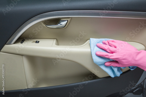 Hand in rubber protective glove with rag cleaning a car interior's door. Early spring cleaning or regular clean up.