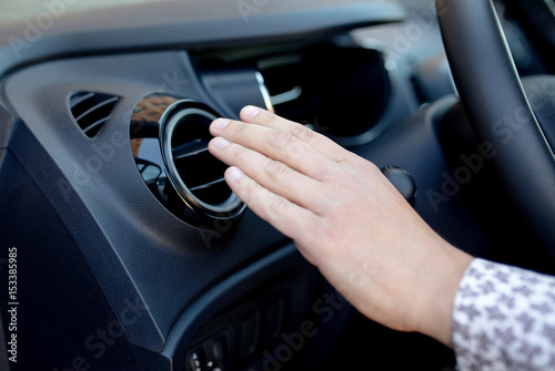 Driver hand on air ventilation grille with power regulator, modern car interior detail