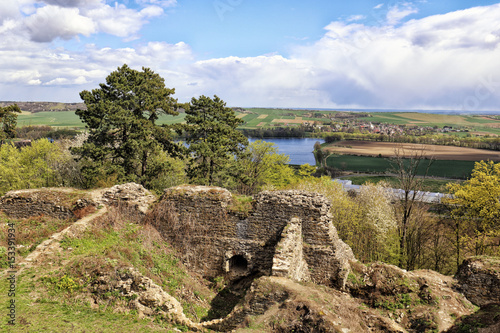 Remains of medieval castle building by the lake and fields photo