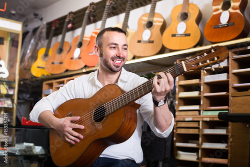 Guy choosing guitar in music shop.