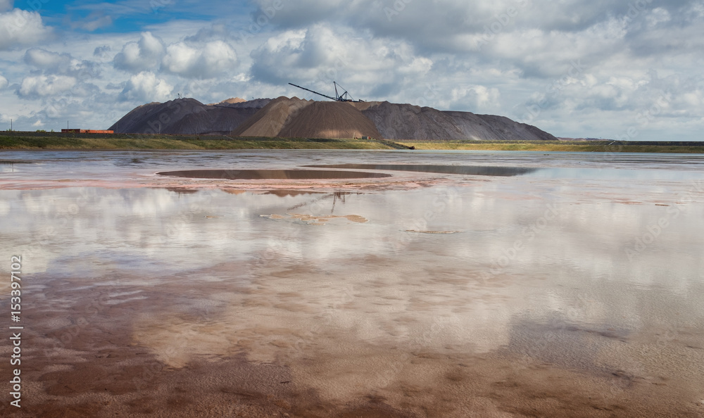 Extracting and mining potassium and magnesium salts.Blue Cloud Sky,Red Water,Large excavator machine ( dragline ) and Huge mountains of waste ore in the extraction of potassium. Belarus, Soligorsk.