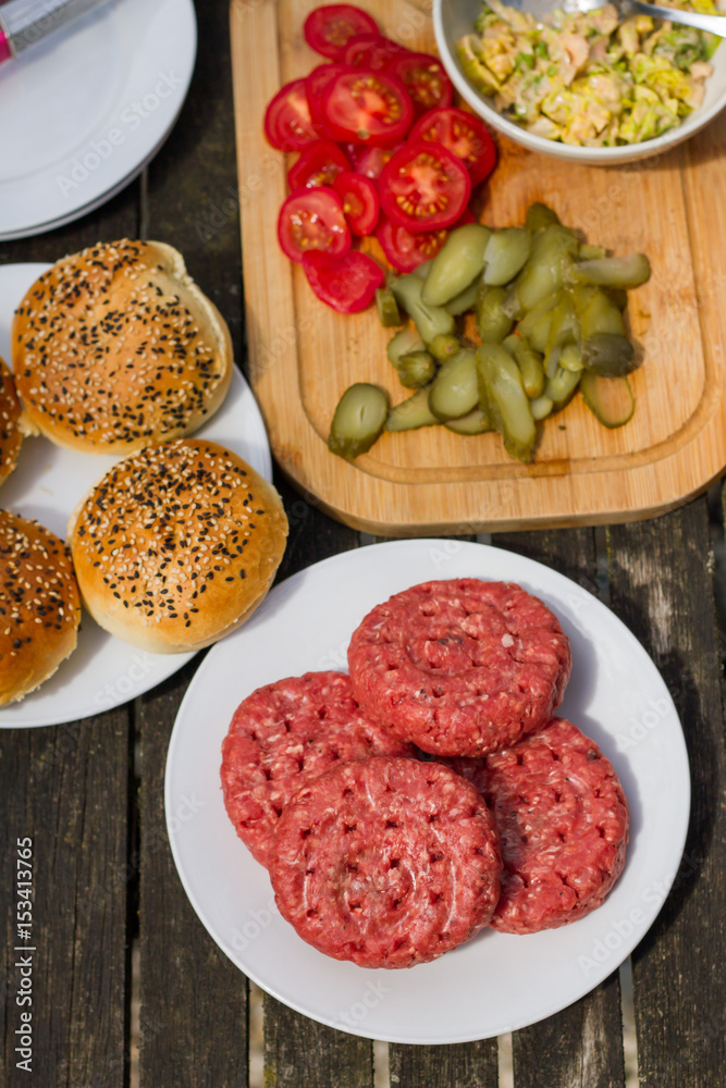 Barbecue, BBQ in the garden. Ingredients. Fresh burger with beef on wooden table. Barbecue, BBQ in the garden. Ingredients. Fresh burger with beef on wooden table.