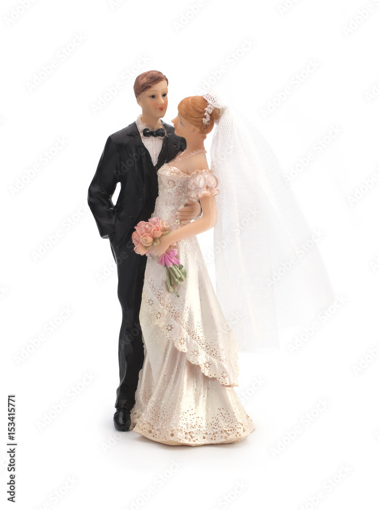 Figurines of a wedding cake on a white background, bride in a dress, bridegroom in a black tuxedo. Isolated