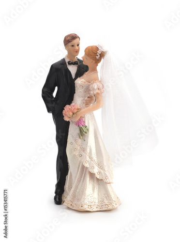 Figurines of a wedding cake on a white background  bride in a dress  bridegroom in a black tuxedo. Isolated