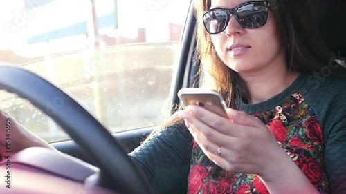 Girl driving a car, driving a car is dangerous, holding a phone in her hands, looking at the monitor. Slow motion. 1920x1080. photo