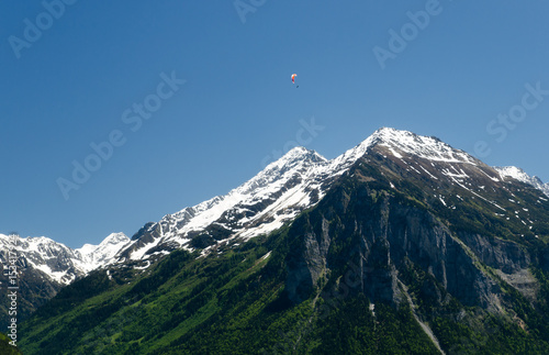 Paragliding in the Swiss Alps above snow covered peaks