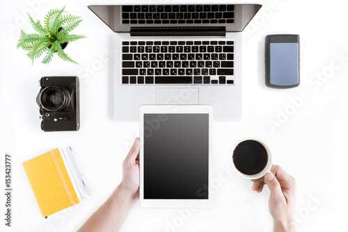 Fototapeta Naklejka Na Ścianę i Meble -  top view of hands holding tablet and coffee cup at modern workplace