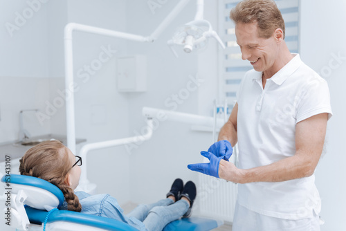 Good qualified dentist putting on special gloves