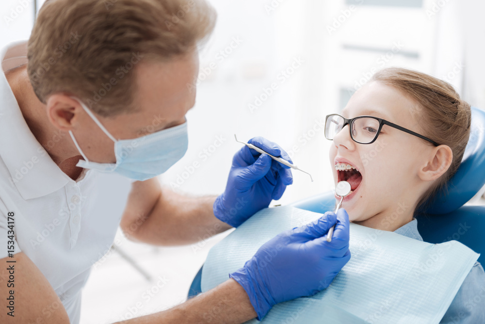 Skillful dentist checking a general condition of his patient Skillful dentist checking a general condition of his patient