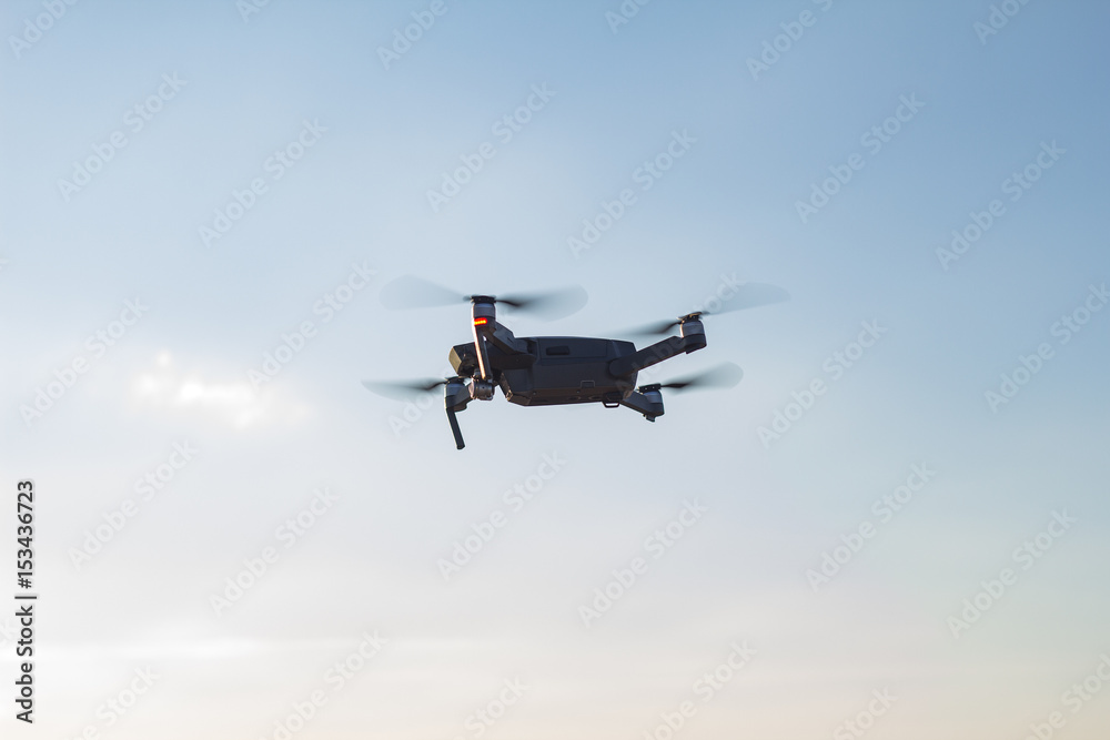 Black drone flying in blue sky 