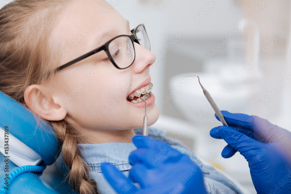 Competent young dentist fixing patients braces Competent young dentist fixing patients braces