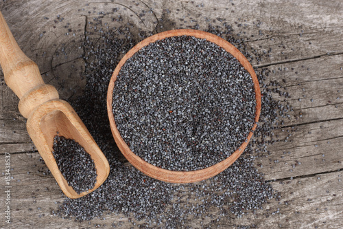  poppy seeds in wooden bowl on wooden background with copy space. top view photo