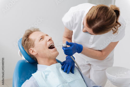Delicate neat dentist performing dental manipulation