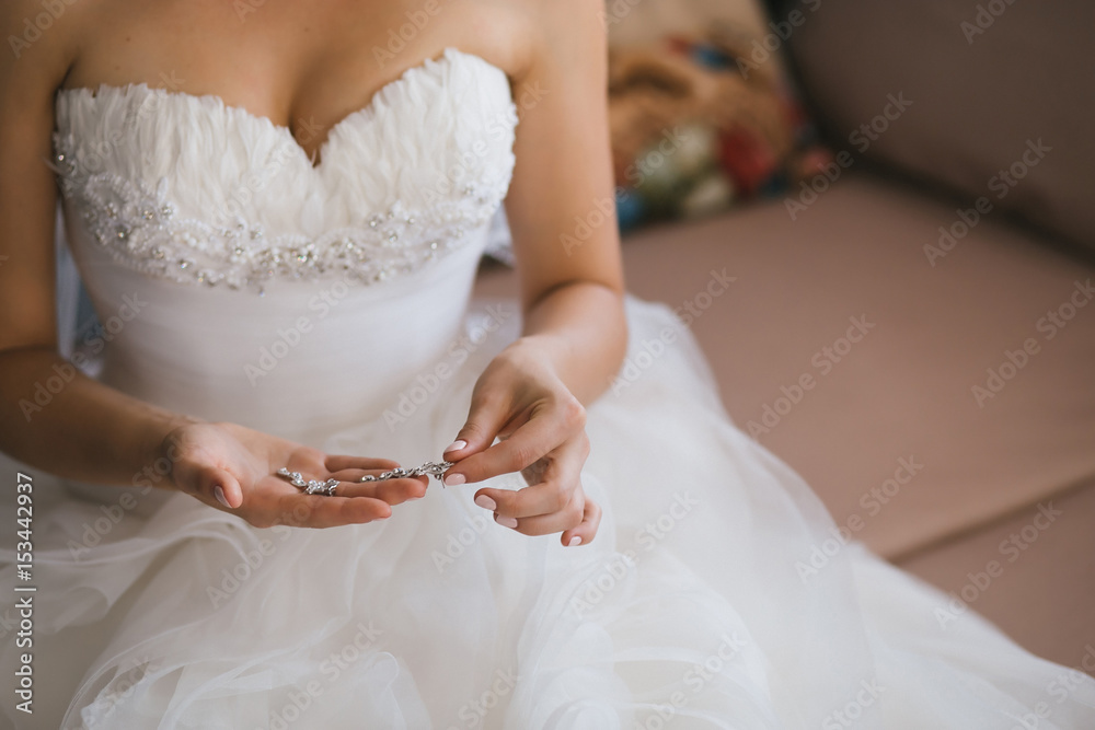 Bride holding silver earrings. Tender hands with jewelry.