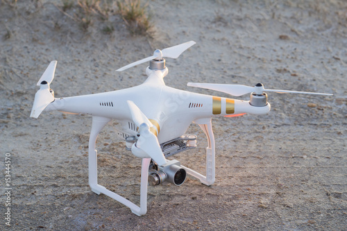 White drone with video camera stand on the sand 