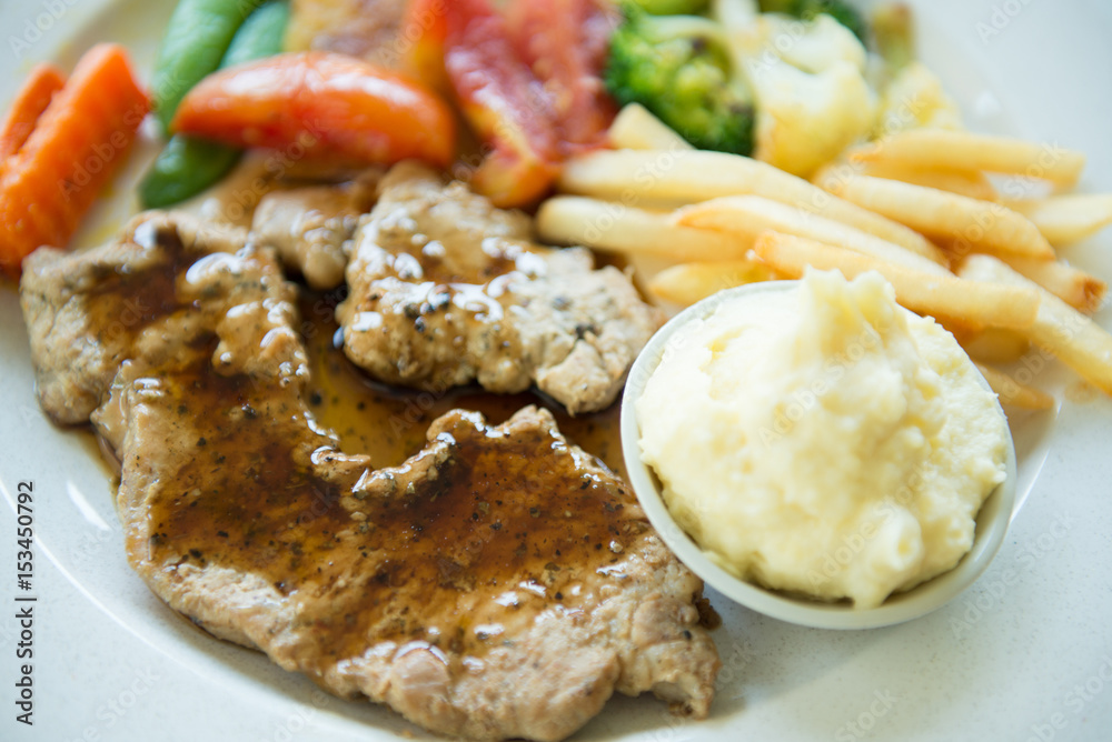 Black pepper pork steak served with mashed potatoes and vegetable on white plate Black pepper pork steak served with mashed potatoes and vegetable on white plate