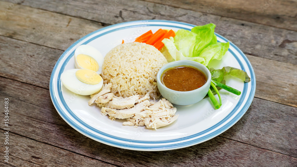 Hainanese chicken rice with boiled egg on a wooden table. Hainanese chicken rice with boiled egg on a wooden table.