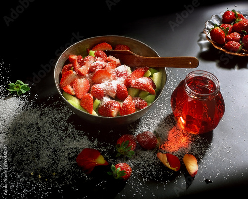 Strawberries, and melon with sugar and sStrawberries, and melon with sugar and sweet on a dark backgroundweet background dark background photo