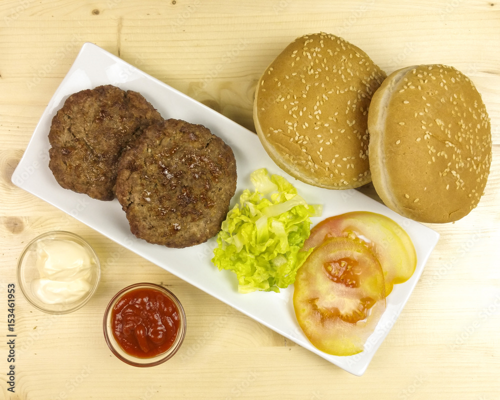 Hamburgers in a plate on wooden background - top view
