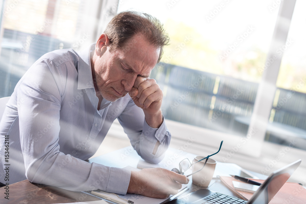 Tired businessman sitting in office, light rays effect Tired businessman sitting in office, light rays effect
