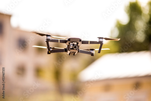 drone quad copter with high resolution digital camera flying hovering in the blue sky over the city