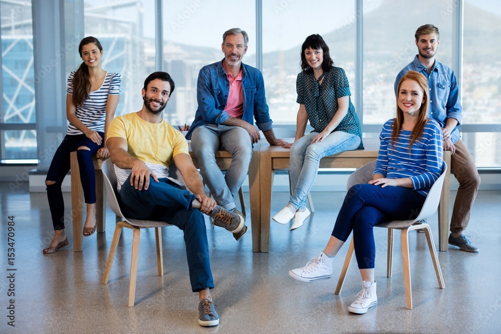 Fototapeta premium Smiling creative business sitting on chair and desk in office