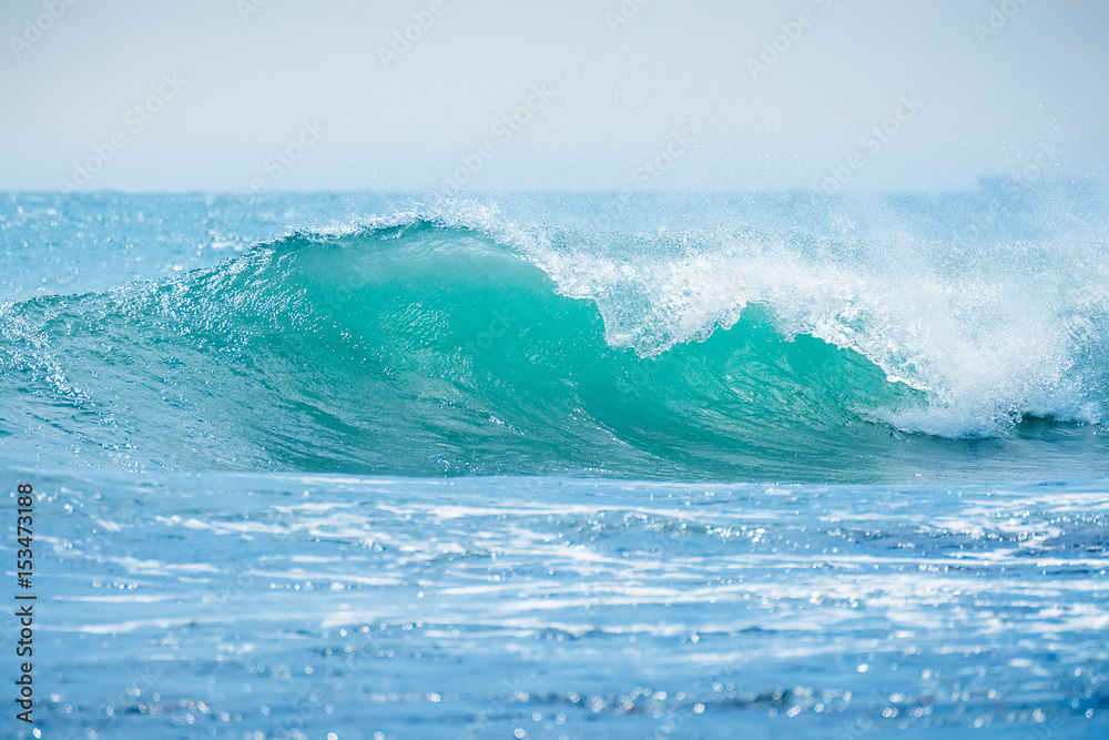 Blue wave in tropical ocean. Wave crashing in sunny day