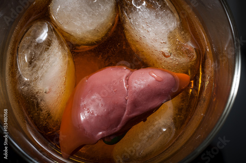 Alcoholic liver damage and cirrhosis concept with a liver in a glass of alcohol. Cirrhosis is most commonly caused by alcoholism, hepatitis B or C or non-alcoholic fatty liver disease photo