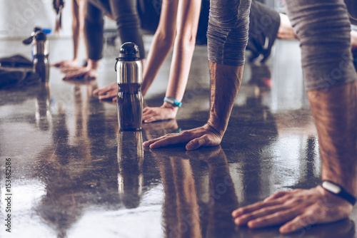 group of athletic young people in sportswear doing push ups or plank at the gym, group fitness concept