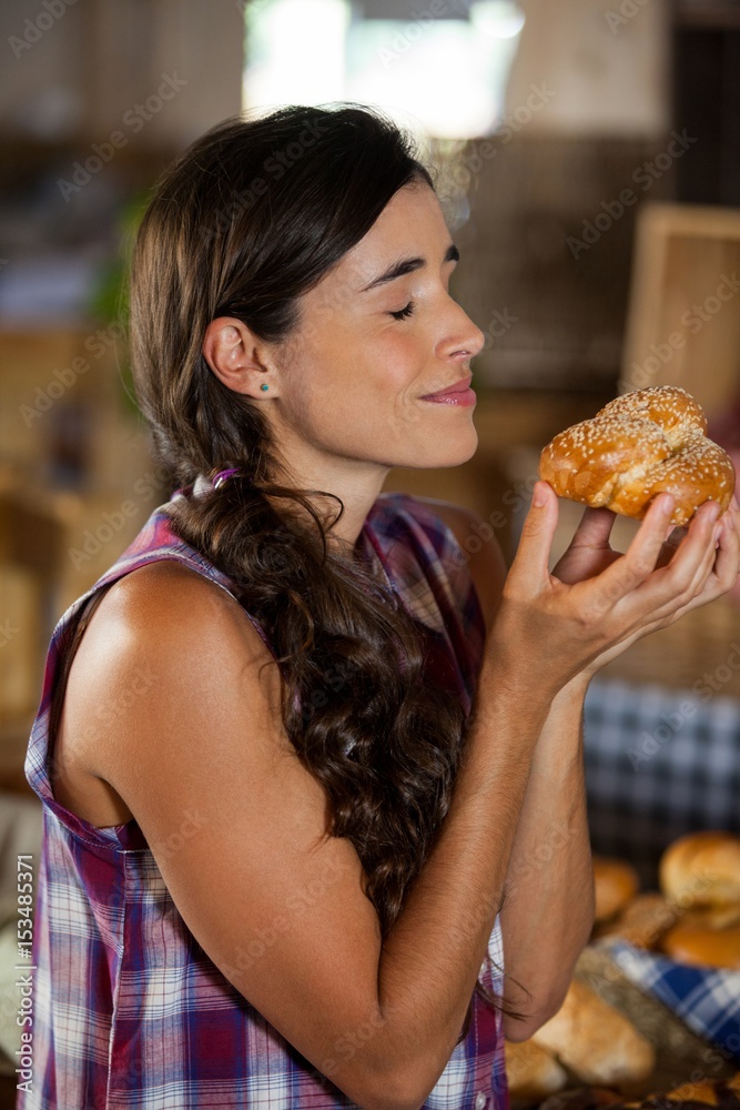 Smiling woman smelling a bread at counter Smiling woman smelling a bread at counter