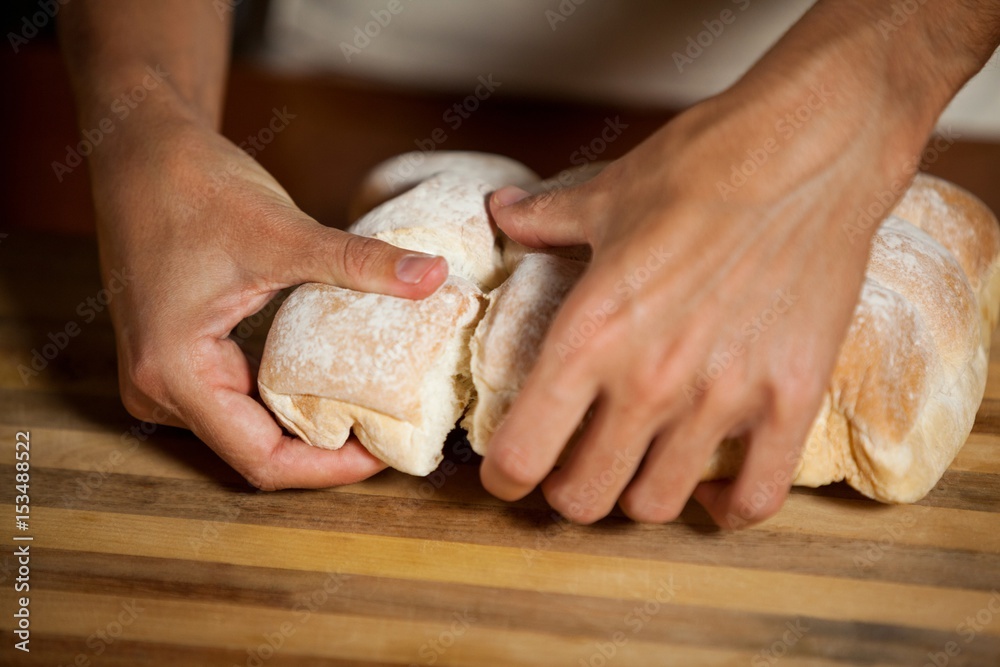 Male staff tearing a bun in bakery shop