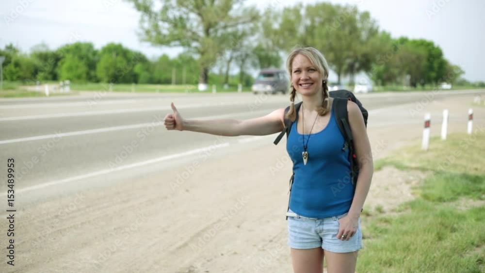 A positive girl hitch-hiked. The girl stops cars on the road. A positive girl hitch-hiked. The girl stops cars on the road.