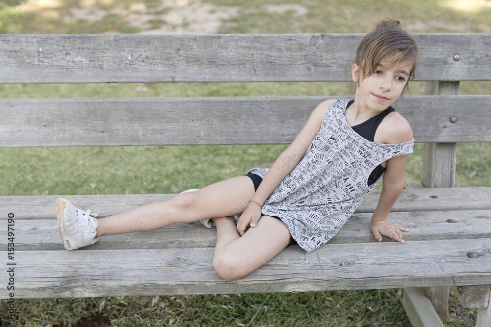 Naklejka premium Girl sitting on a wooden bench