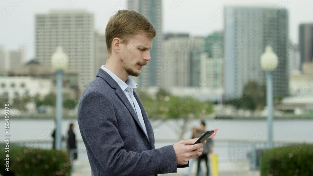 Young bearded guy is buying something over the Internet on a street of Coronado, San Diego Young bearded guy is buying something over the Internet on a street of Coronado, San Diego