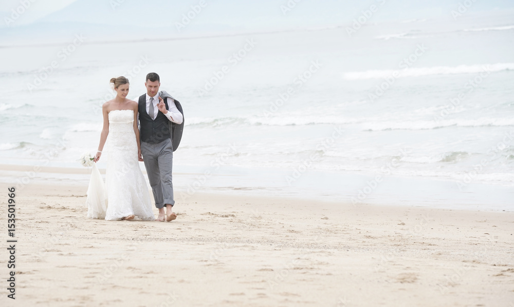 Happy bride and groom walking on the beach Happy bride and groom walking on the beach