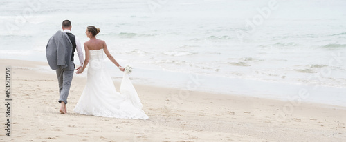 Photo Back view of bride and groom walking on the beach