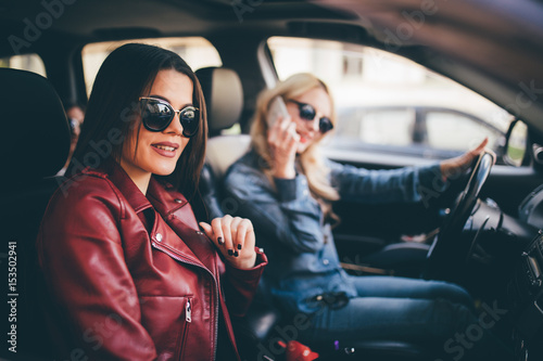 Two young women friends talking together in the o car as they go on a road trip while driver speak on phone © F8  \ Suport Ukraine