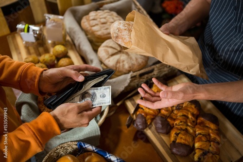 Customer paying bill by cash at bread counter photo