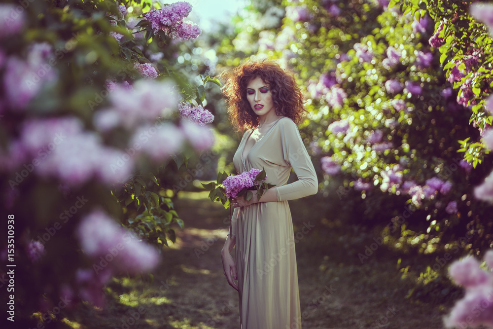 Young woman in alley of lilac bushes in the garden. Young woman in alley of lilac bushes in the garden.