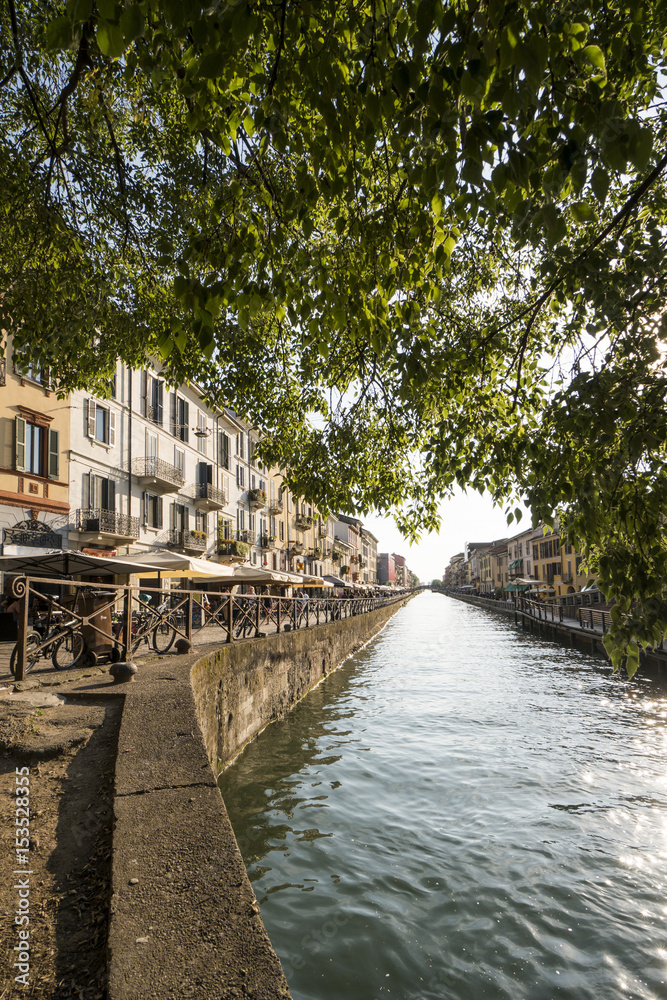 Fototapeta premium The Naviglio Grande canal waterway in Milan, Italy, at sunset. This district is famous for its restaurants, cafes, pubs and nightlife.