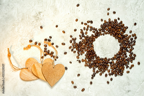 Three wooden hearts as a symbol of love of coffee and a circle of coffee beans, top view. Copy space.