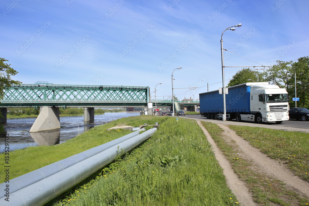 Transportation in city: railway bridge, industrial pipes and road transport. Kaunas, Lithuania – May 17, 2017: Industrial landscape with Green Railway Bridge. Transportation in city: railway bridge, industrial pipes and road transport. Kaunas, Lithuania – May 17, 2017: Industrial landscape with Green Railway Bridge.