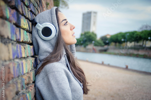Young and sad woman listening music from her headphones outdoor photo