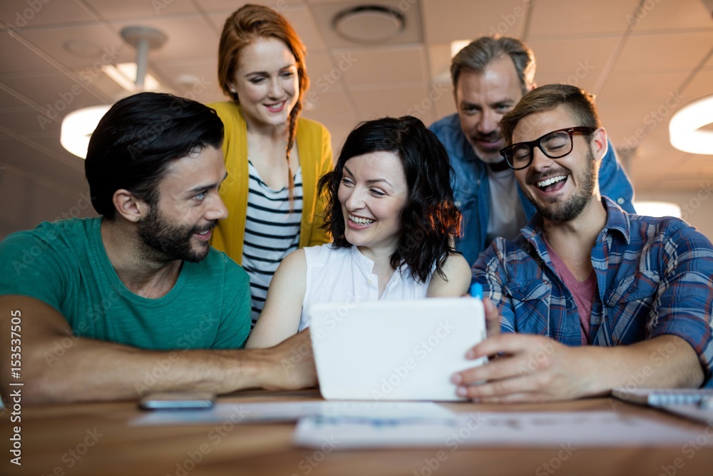 Happy creative business team discussing over digital tablet Happy creative business team discussing over digital tablet