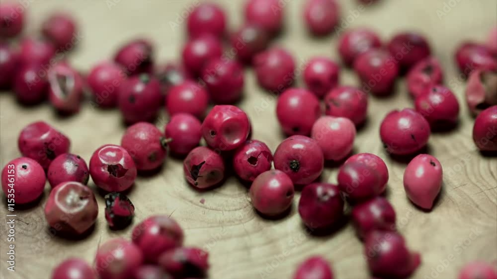 Scattered rose pepper on the wooden cutting board, macro, statics Scattered rose pepper on the wooden cutting board, macro, statics