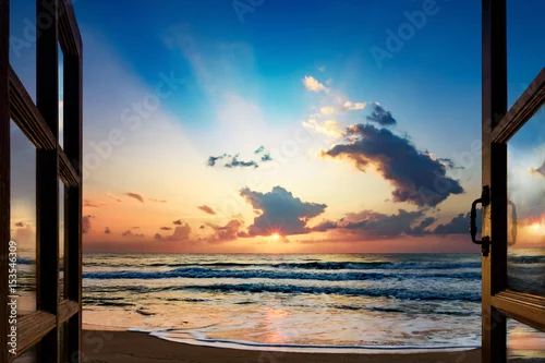 Fototapeta Widok wschodu słońca nad morzem z otwartego okna